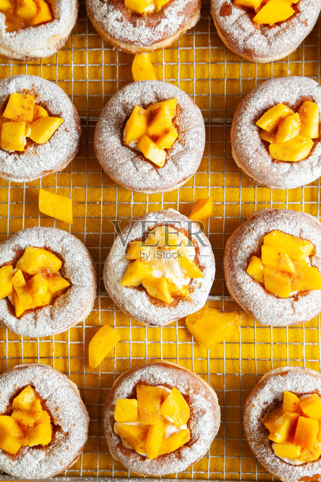 芒果口味的奶油蛋卷甜甜圈，新鲜出炉，糖包着蛋奶沙司。照片摄影图片