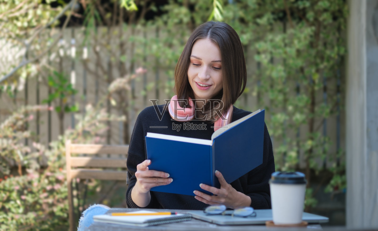 坐在公园长椅上读书的年轻女子的肖像照片摄影图片