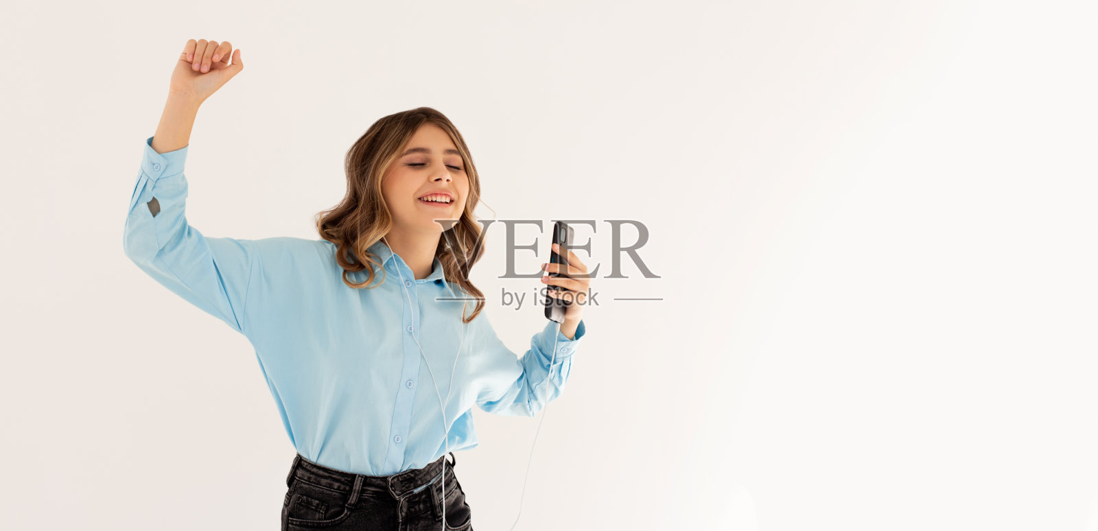 年轻女子用手机听白色背景音乐照片摄影图片