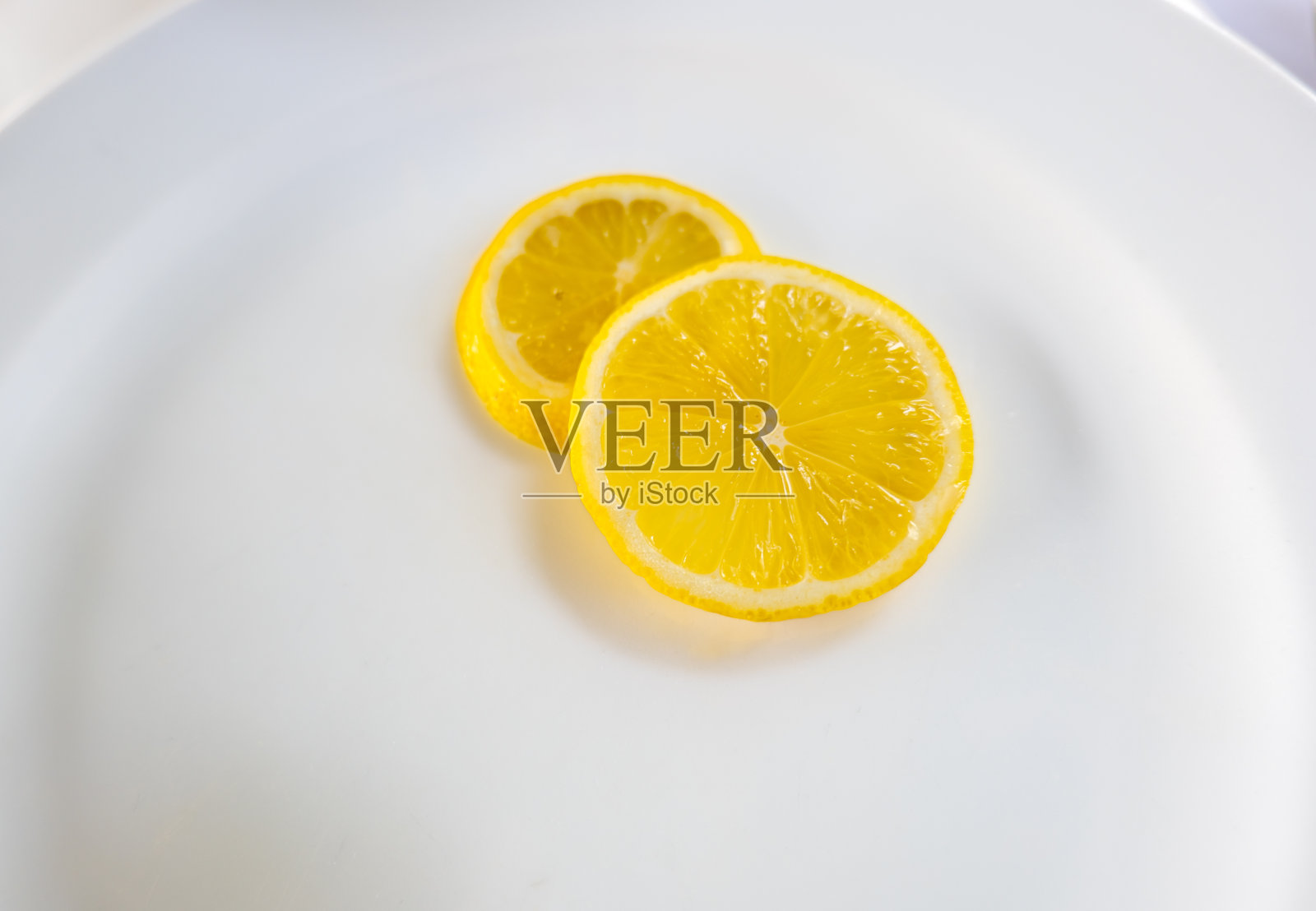 2片柠檬片，白色盘子背景的柠檬片。照片摄影图片