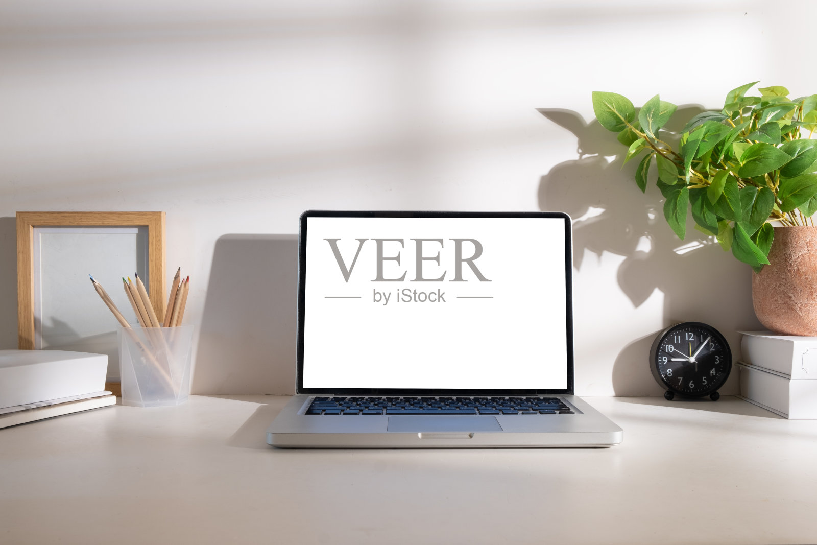 笔记本电脑与空显示器，记事本，咖啡杯，文具和室内植物在白色的桌子上。照片摄影图片