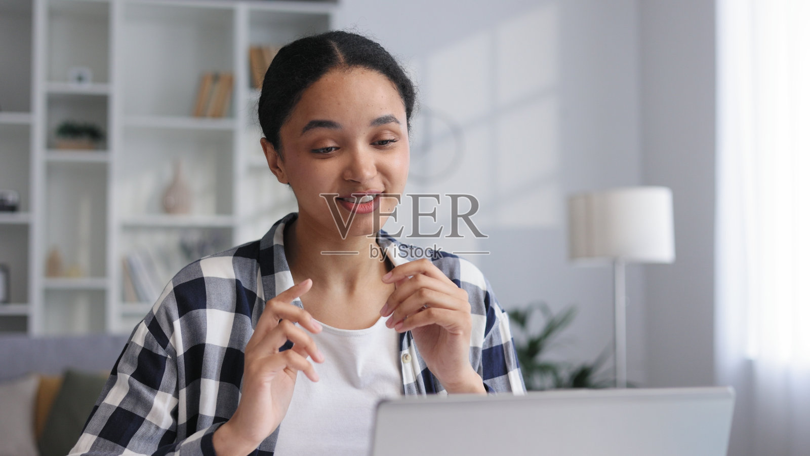 迷人的年轻女商人在家工作，微笑着，在视频通话中聊天。迷人的年轻非裔美国女学生在家学习，远程学习，展示她的作品。照片摄影图片