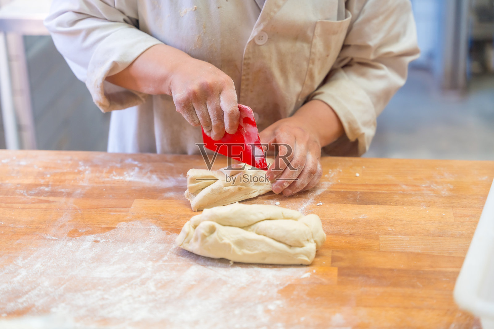 在手工面包店的车间里，女面包师在切面团照片摄影图片