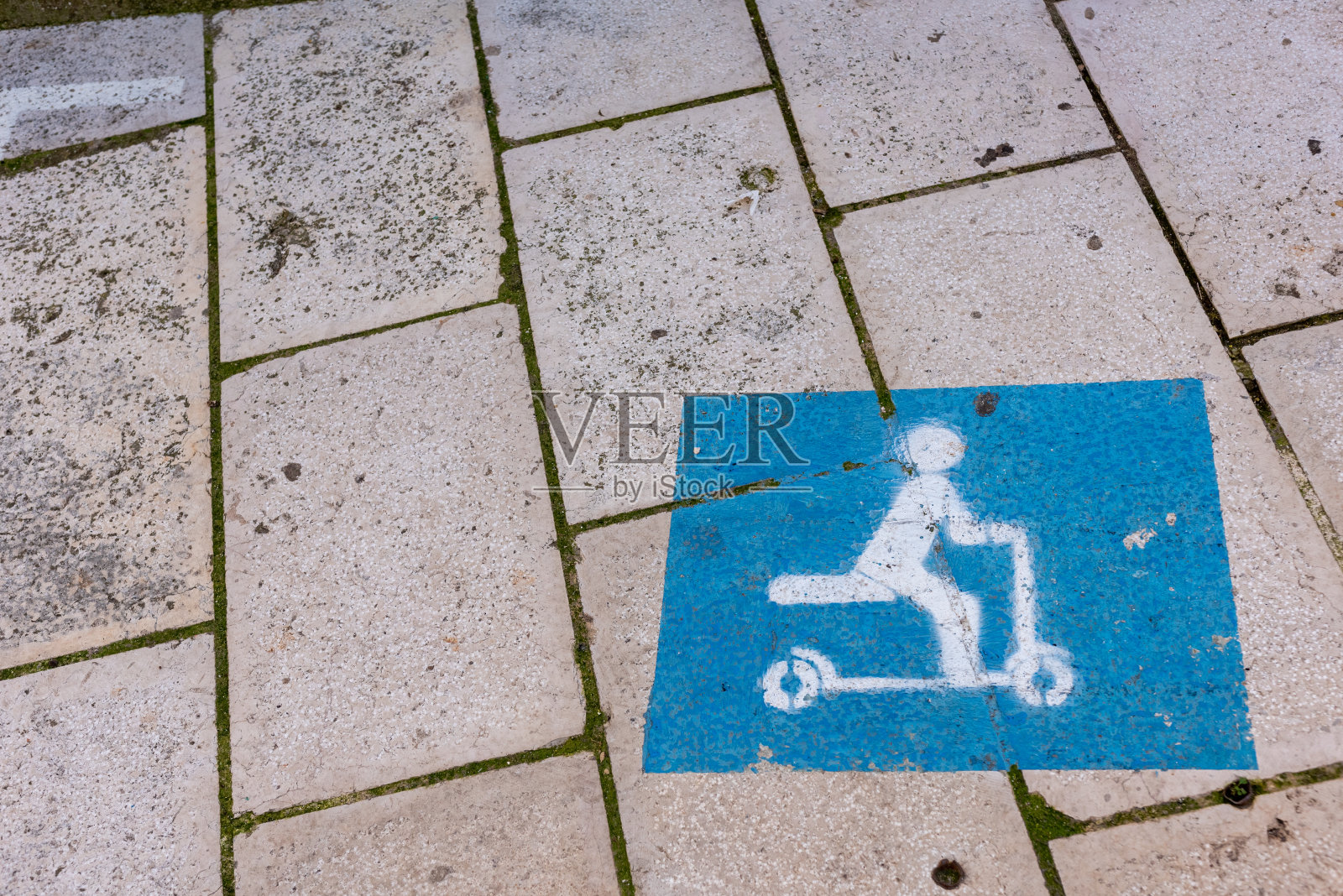 用喷漆涂在地板上的交通标志，描绘了一个骑着踏板车的人照片摄影图片