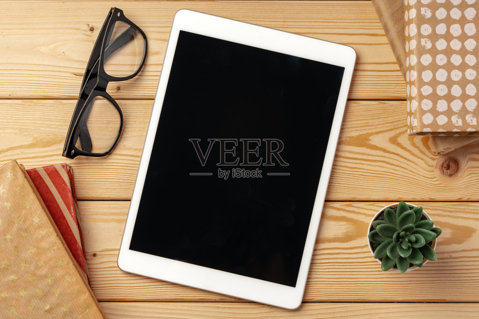 木桌的俯视图，上面有黑色屏幕的白色数字平板电脑照片摄影图片