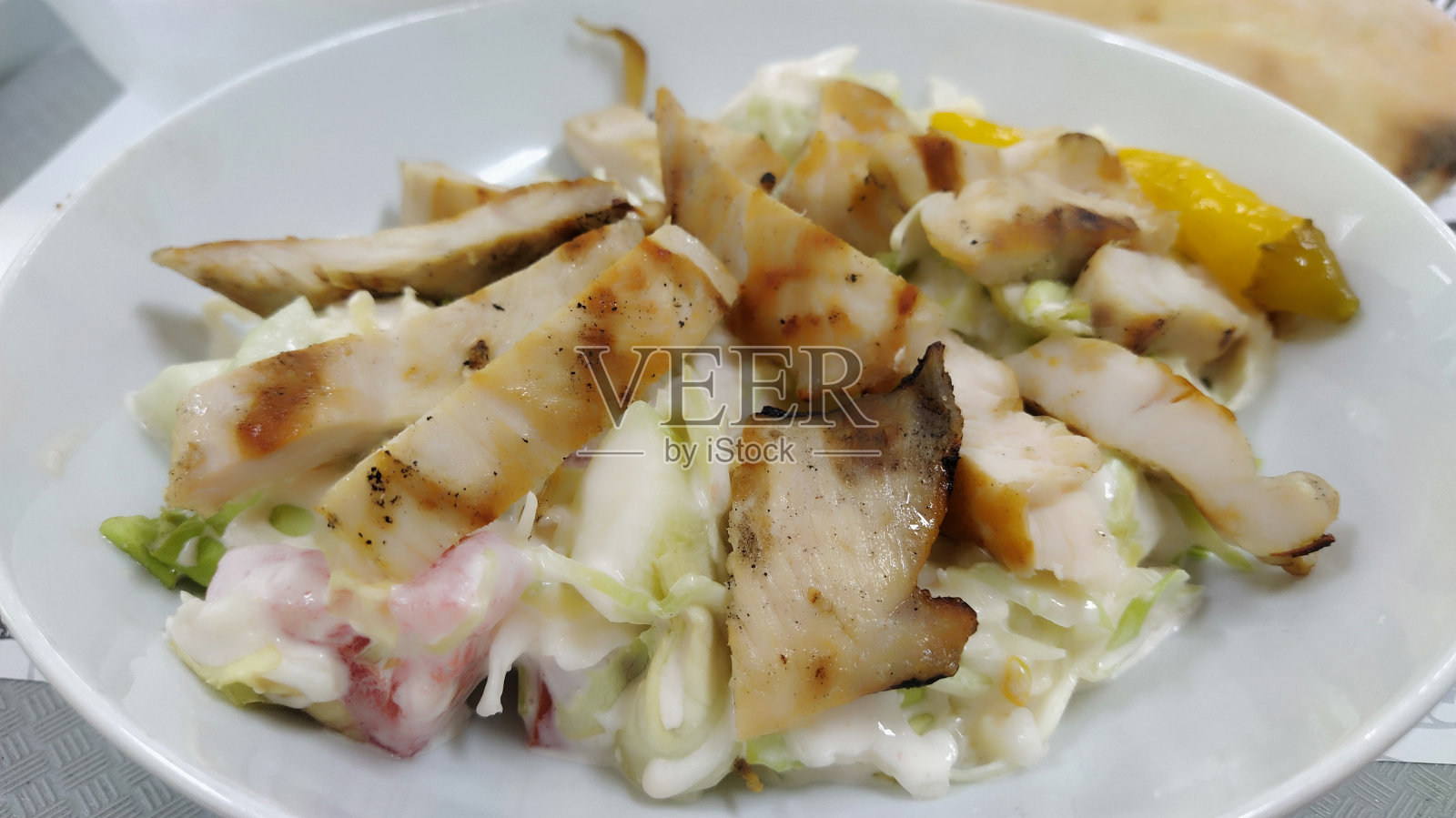 凯撒蔬菜沙拉。一道很受欢迎的美国菜。餐馆里白色盘子里的蔬菜沙拉和烤鸡。黄瓜片，番茄片，生菜片，鸡肉片，拌上蛋黄酱照片摄影图片