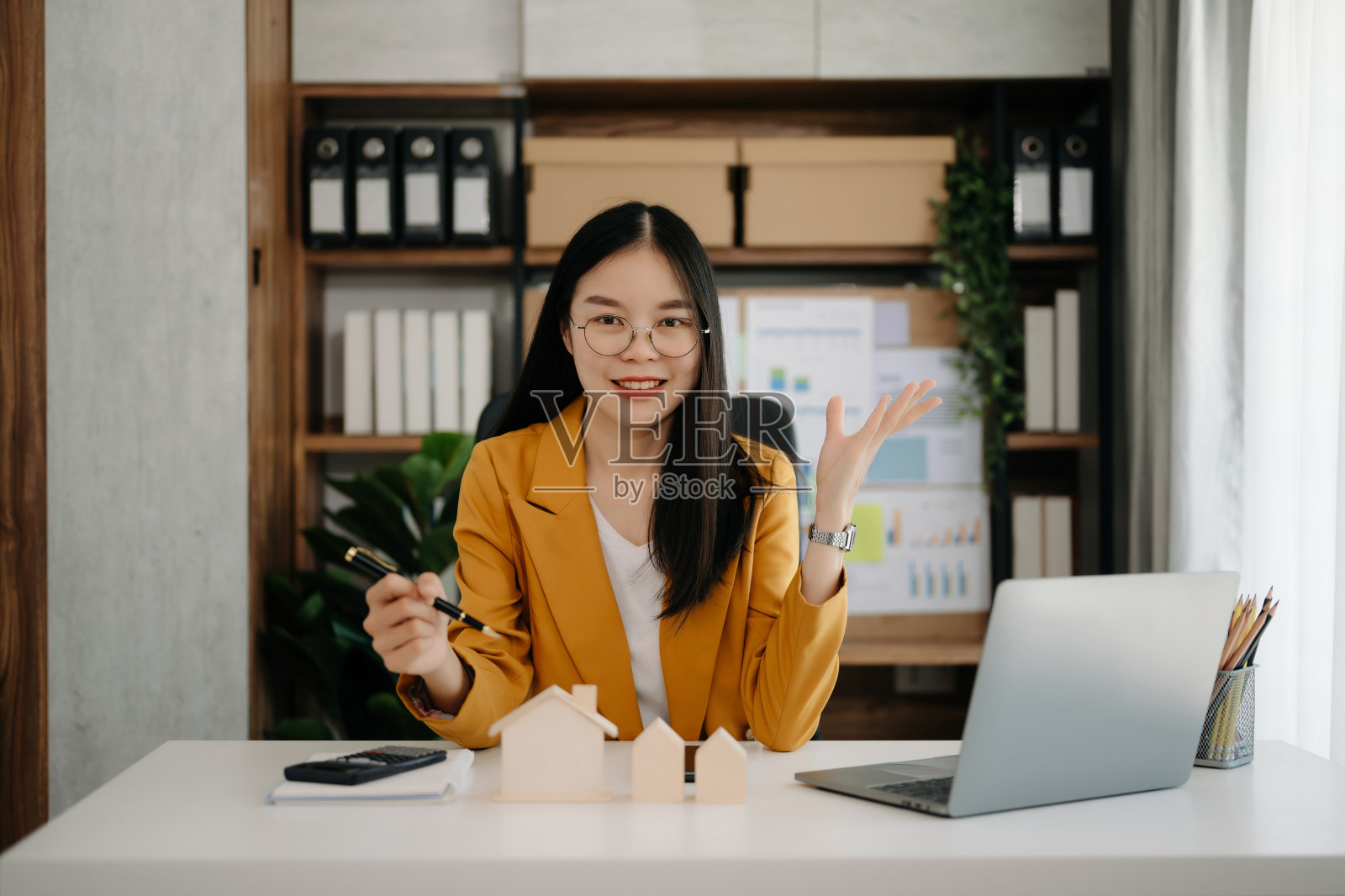 年轻的房地产中介工作人员在办公室的桌子上放着笔记本电脑和平板电脑，旁边是小房子。照片摄影图片