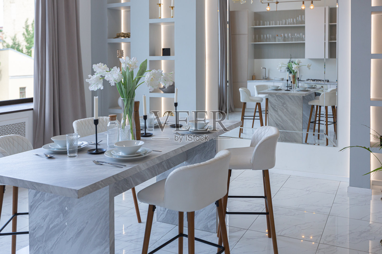 简约的光优雅的豪华设计，现代宽敞的一室公寓，厨房区，卧室和沙发后面的巨大镜子。地板上铺着瓷砖，天花板很高。照片摄影图片