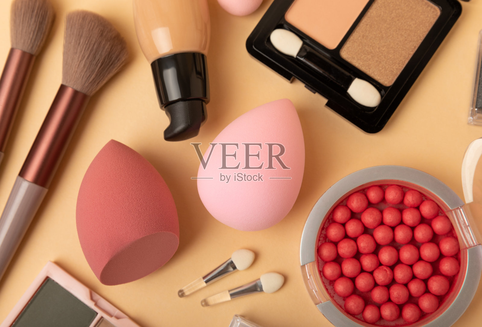 化妆机、粉底、粉底和睫毛膏，底色为米色。美丽和时尚。化妆品配件。美丽的概念照片摄影图片