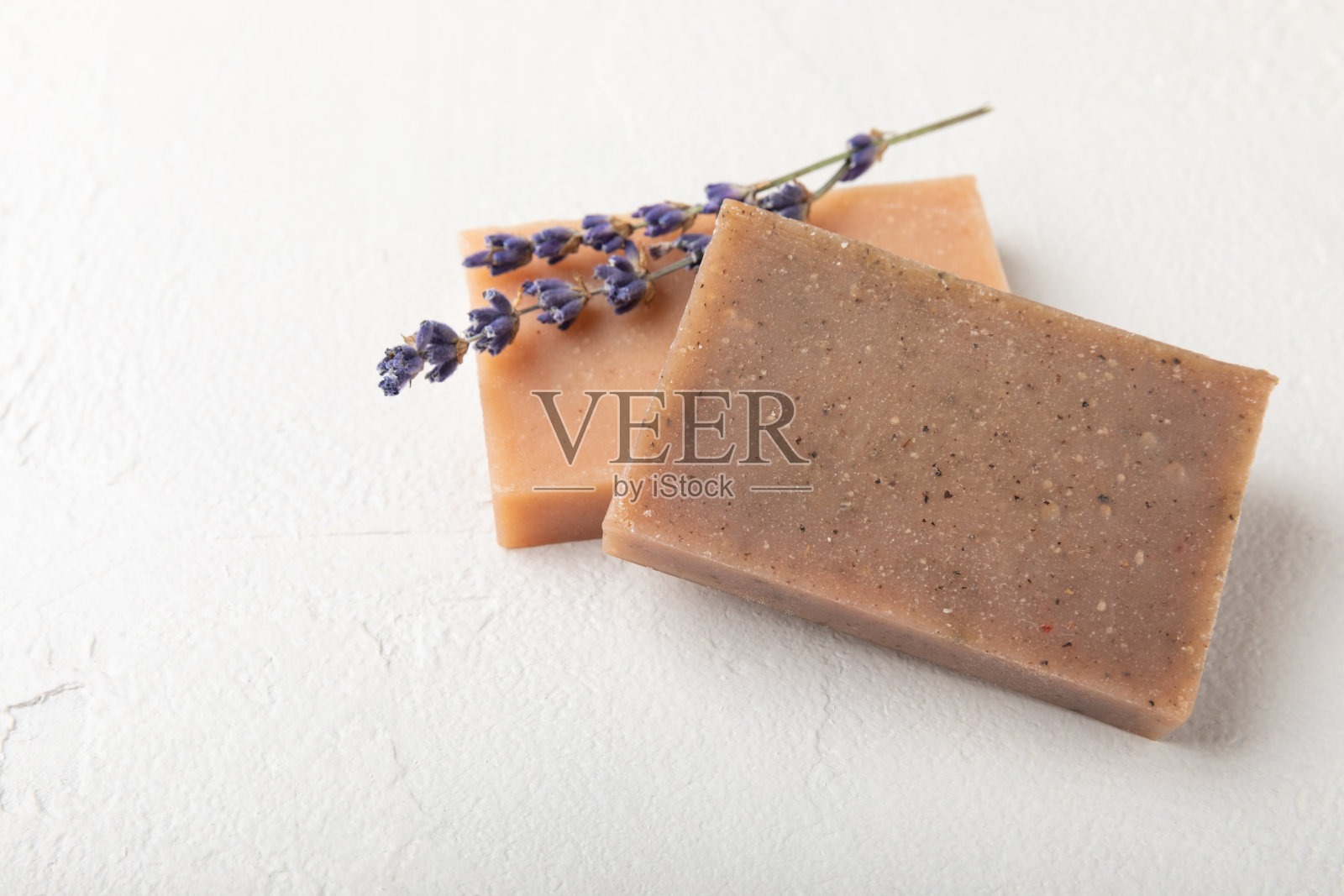 天然薰衣草香皂与薰衣草花在白色水泥背景。手工肥皂。含有精油的化妆品。水疗产品。文本空间。平的。照片摄影图片