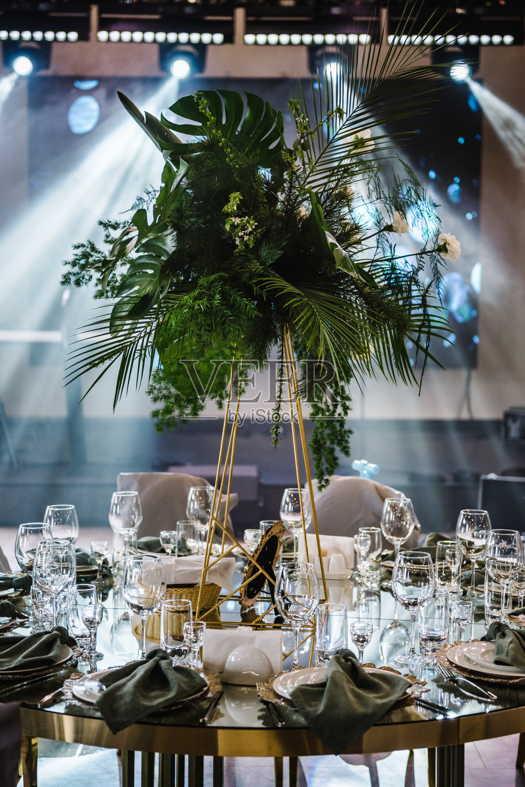 宴会厅装饰组成花卉绿色植物。豪华婚宴。摆好桌子，摆好餐具。生日派对的时髦装饰。客人用的圆桌，盘子，杯子，绿色餐巾。照片摄影图片