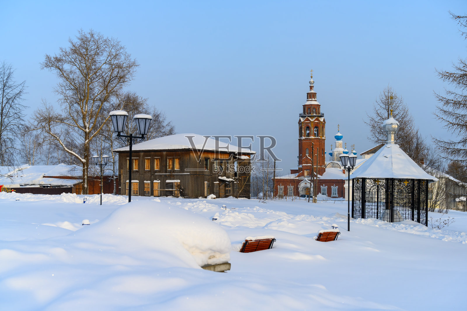 Cherdyn省(Perm地区，俄罗斯)的冬季城市公园，有历史悠久的教堂、木屋、灯笼和深埋在雪中的长凳照片摄影图片