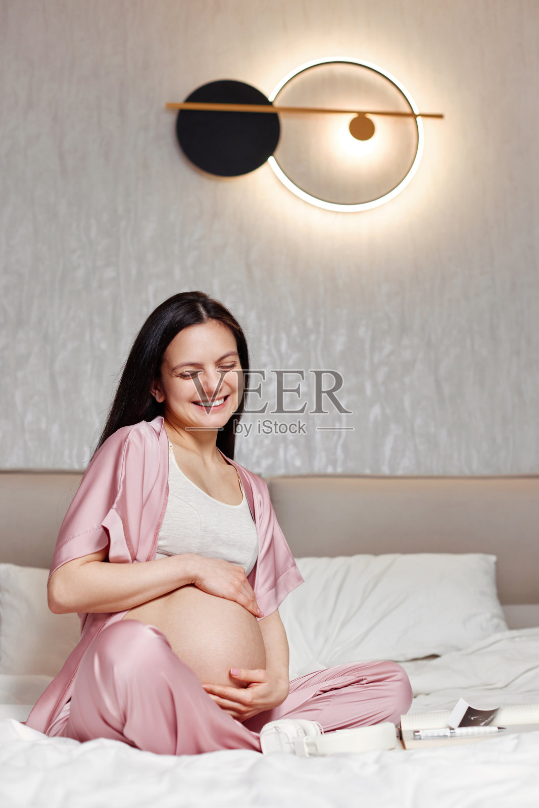 孕妇坐在床上摸肚子照片摄影图片