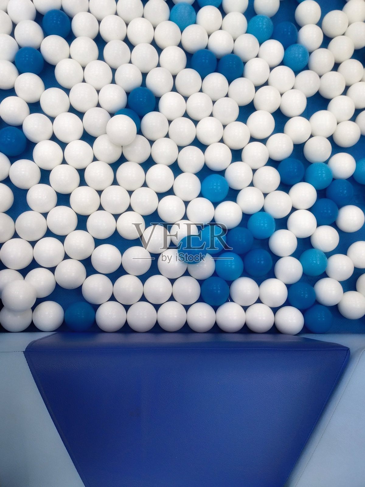 蓝色和白色的塑料玩具球围绕着皮革覆盖的软垫长凳照片摄影图片