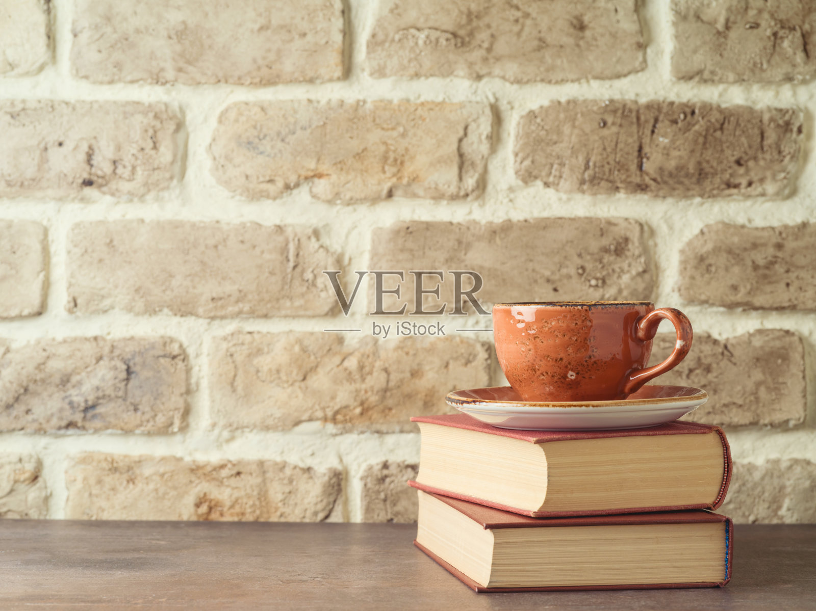 咖啡杯和书在砖墙背景的桌子上照片摄影图片