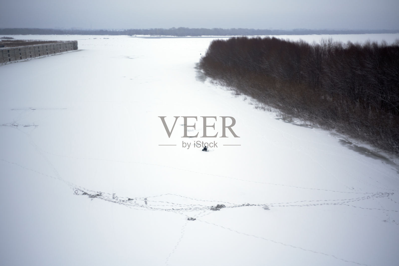 钓鱼洞附近冰面上渔民的脚印。照片摄影图片