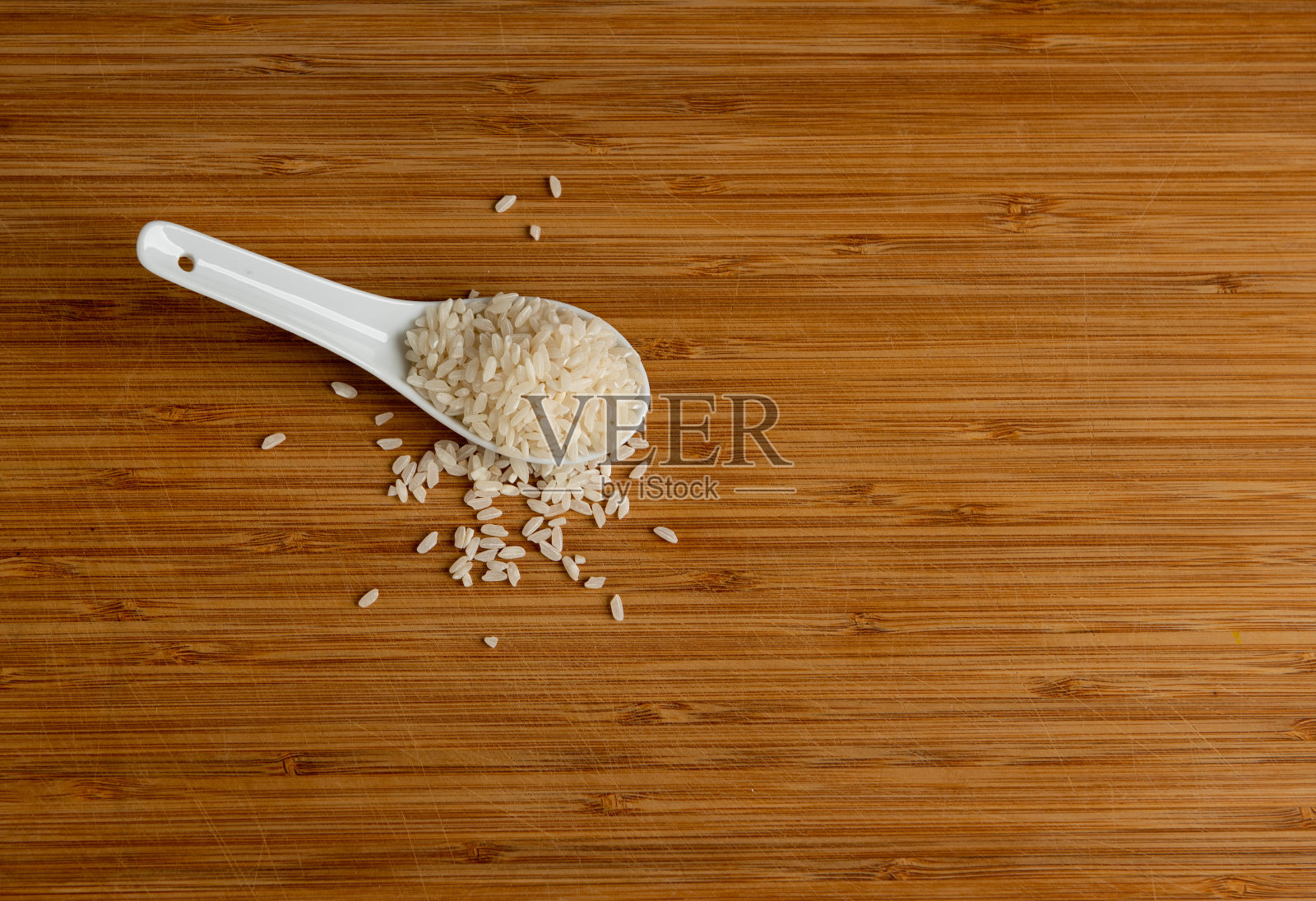 木桌上放着白米饭，还有一把勺子照片摄影图片