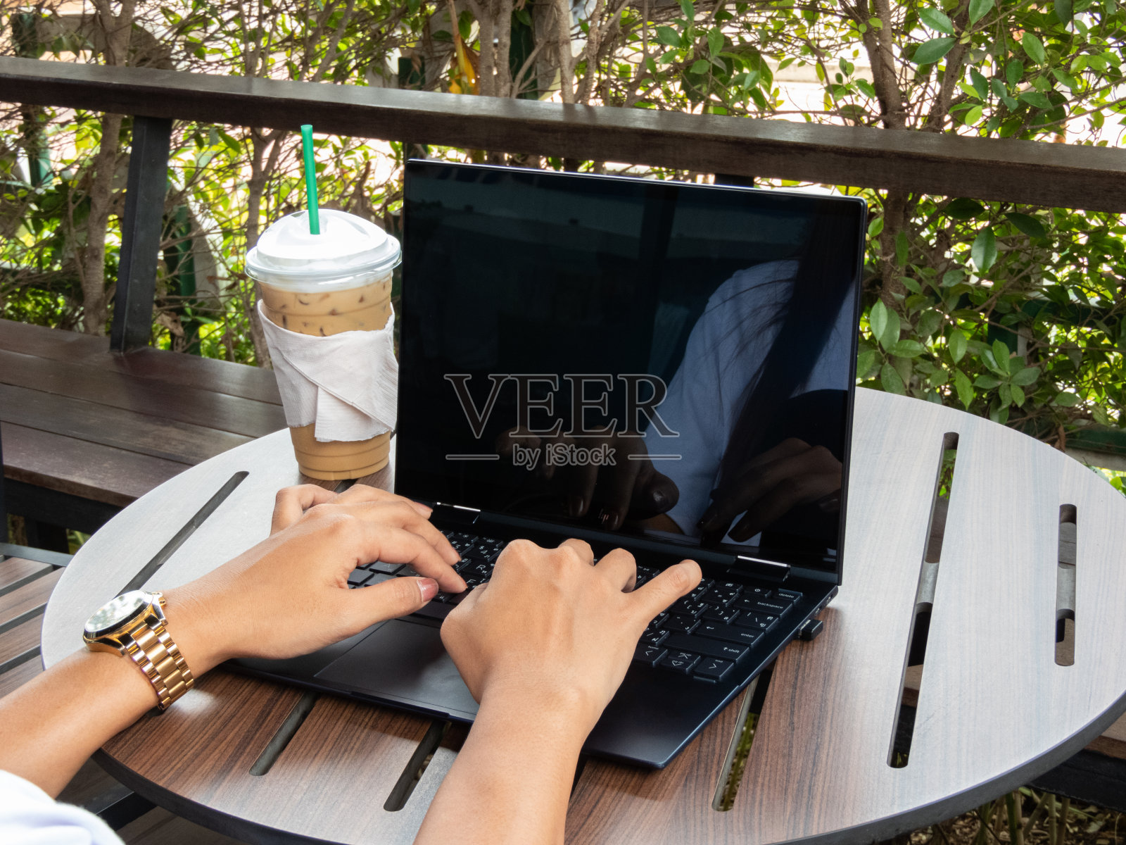 一杯咖啡在她身边，一个年轻女子的手优雅地操纵着笔记本电脑，沉浸在网上购物的便利和兴奋中，她探索着一个充满无限可能性的世界。照片摄影图片