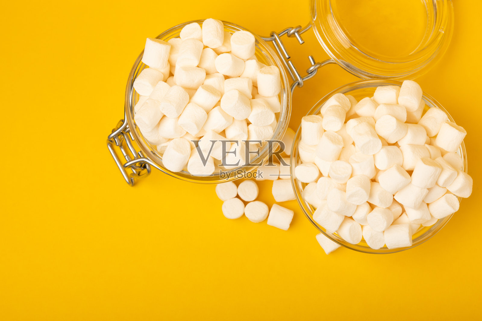 黄色背景上的松散棉花糖。白色的棉花糖平铺。甜食和零食当零食。咀嚼糖果的特写。副本的空间。放文字的地方。冬季食物概念。照片摄影图片