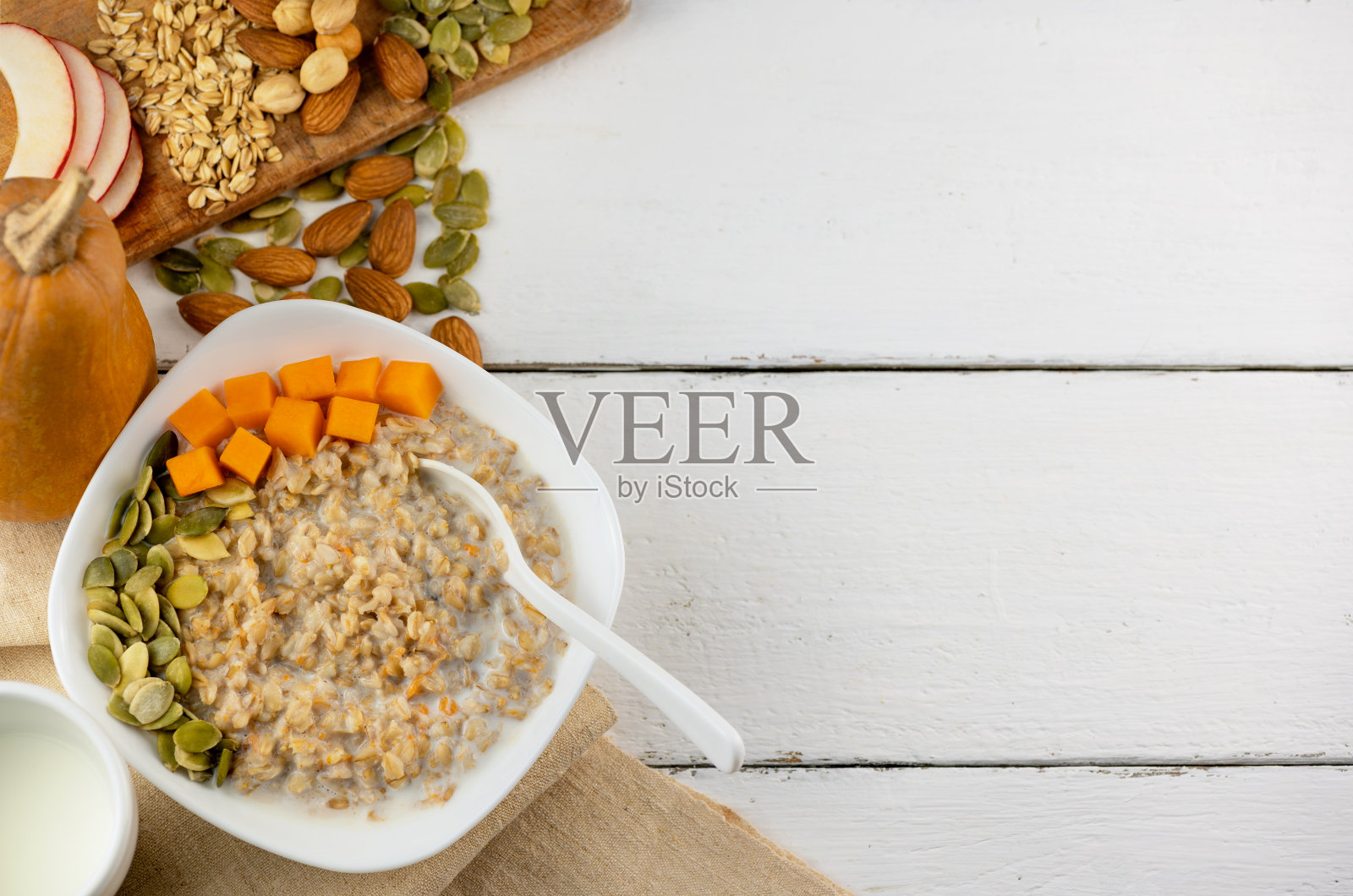 以南瓜和南瓜子、坚果为背景的燕麦粥。健康的食物和复制空间照片摄影图片