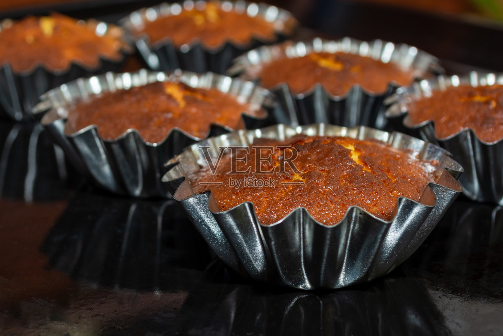 在烤箱的金属模具里烘焙的纸杯蛋糕。有选择性的重点。照片摄影图片