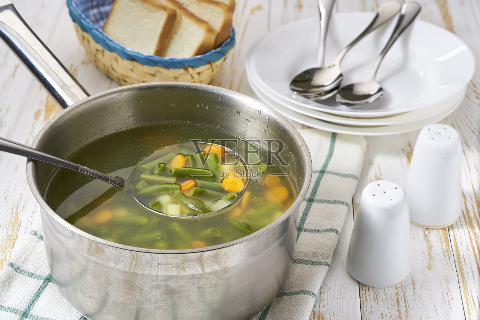 白色木桌上美味的青豆、土豆和胡萝卜蔬菜汤。照片摄影图片