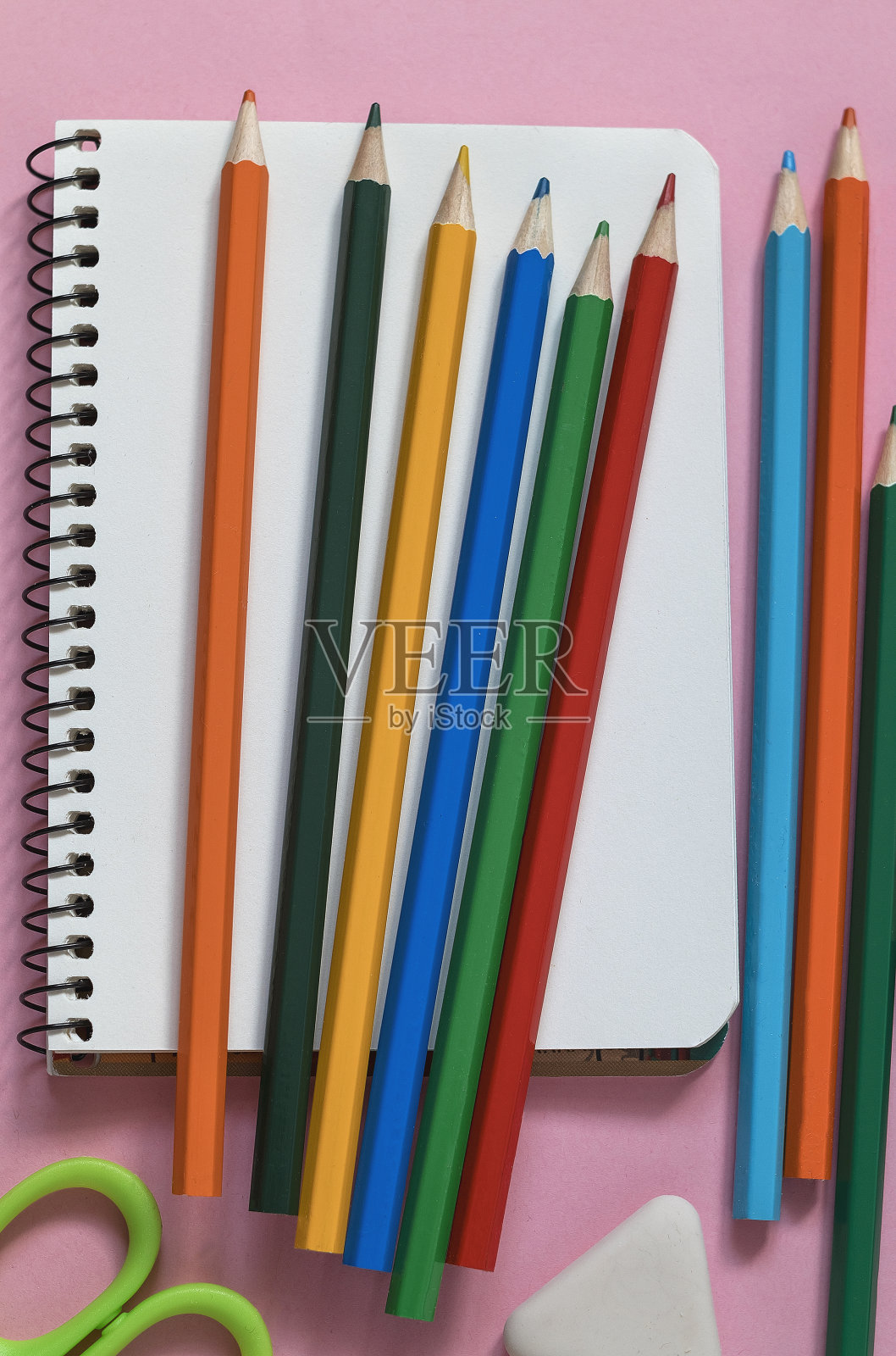 笔记本，彩色铅笔，蜡笔，粉红色的背景。回到学校的概念。照片摄影图片