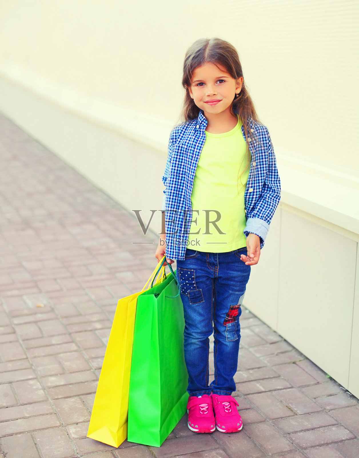 美丽的小女孩的肖像与五颜六色的购物袋在城市街道上照片摄影图片