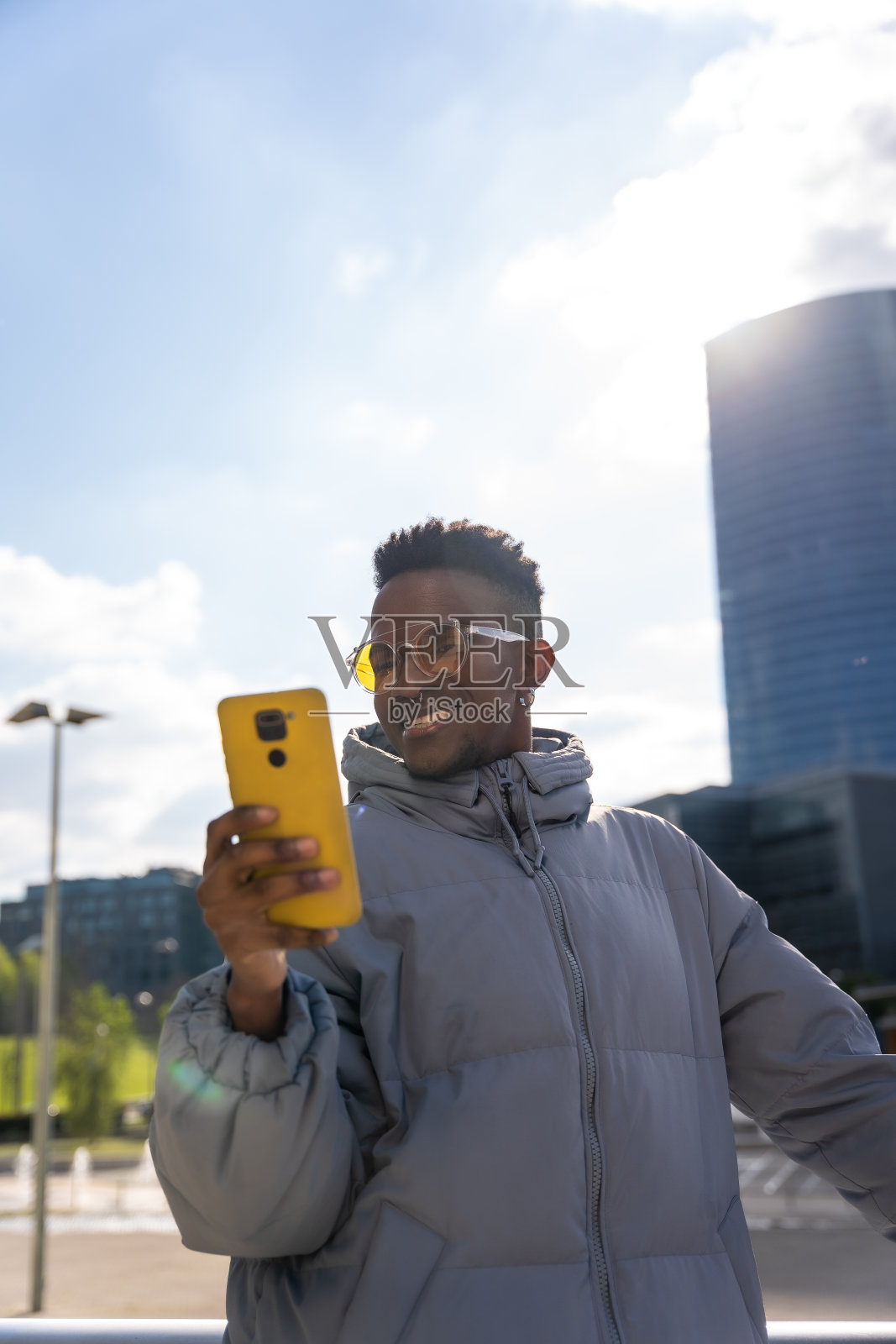 一个拿着手机穿蓝色夹克的黑人在城里浏览社交网络照片摄影图片
