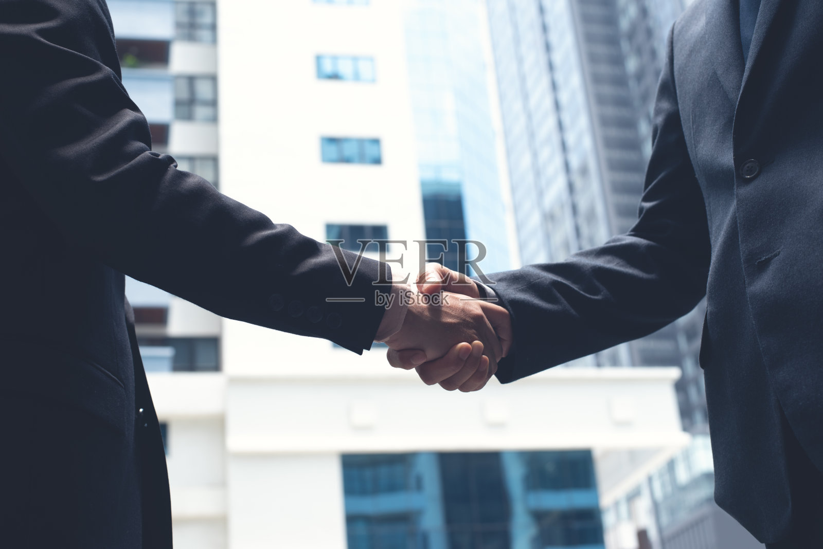 商人握手以城市建筑为背景，商务礼仪、祝贺、并购、商务会议、伙伴关系概念照片摄影图片
