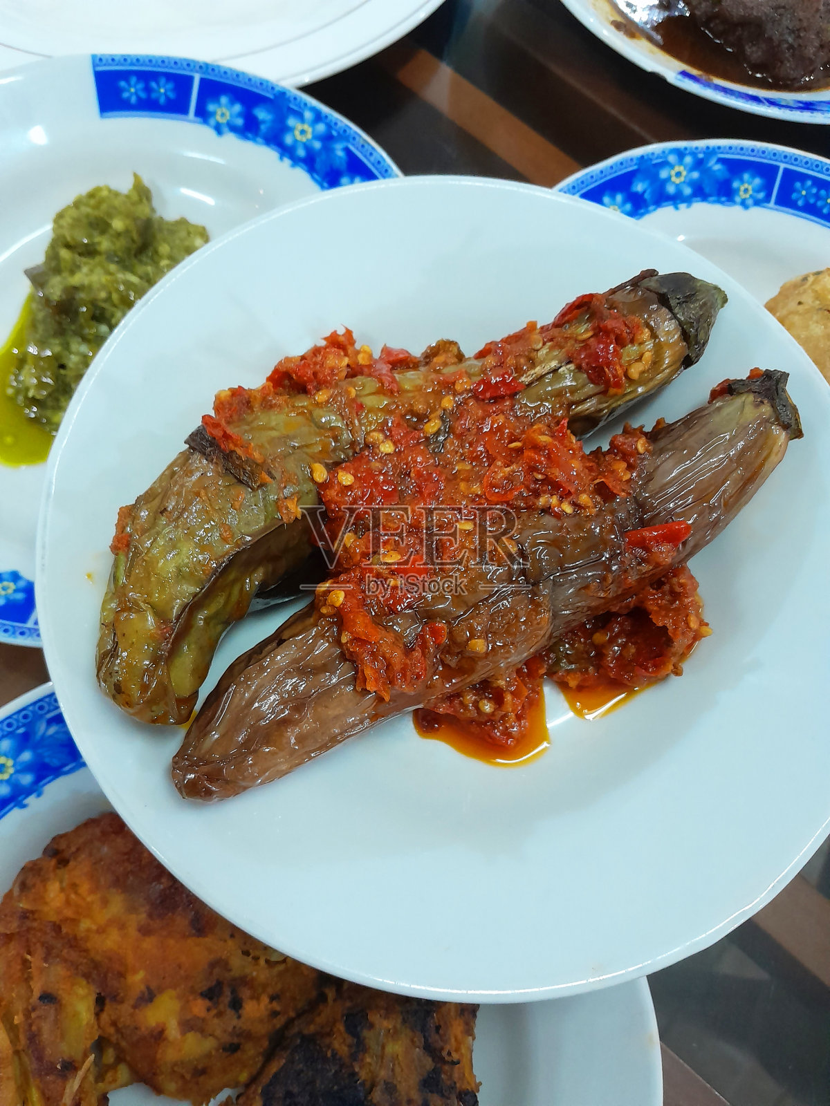 印尼西苏门答腊岛食品- Nasi Padang - terong balado或茄子配红辣椒参巴。将茄子或茄子浸泡在盐水中，然后油炸，然后将红辣椒，青葱和西红柿混合在一起形成辛辣的参巴。照片摄影图片