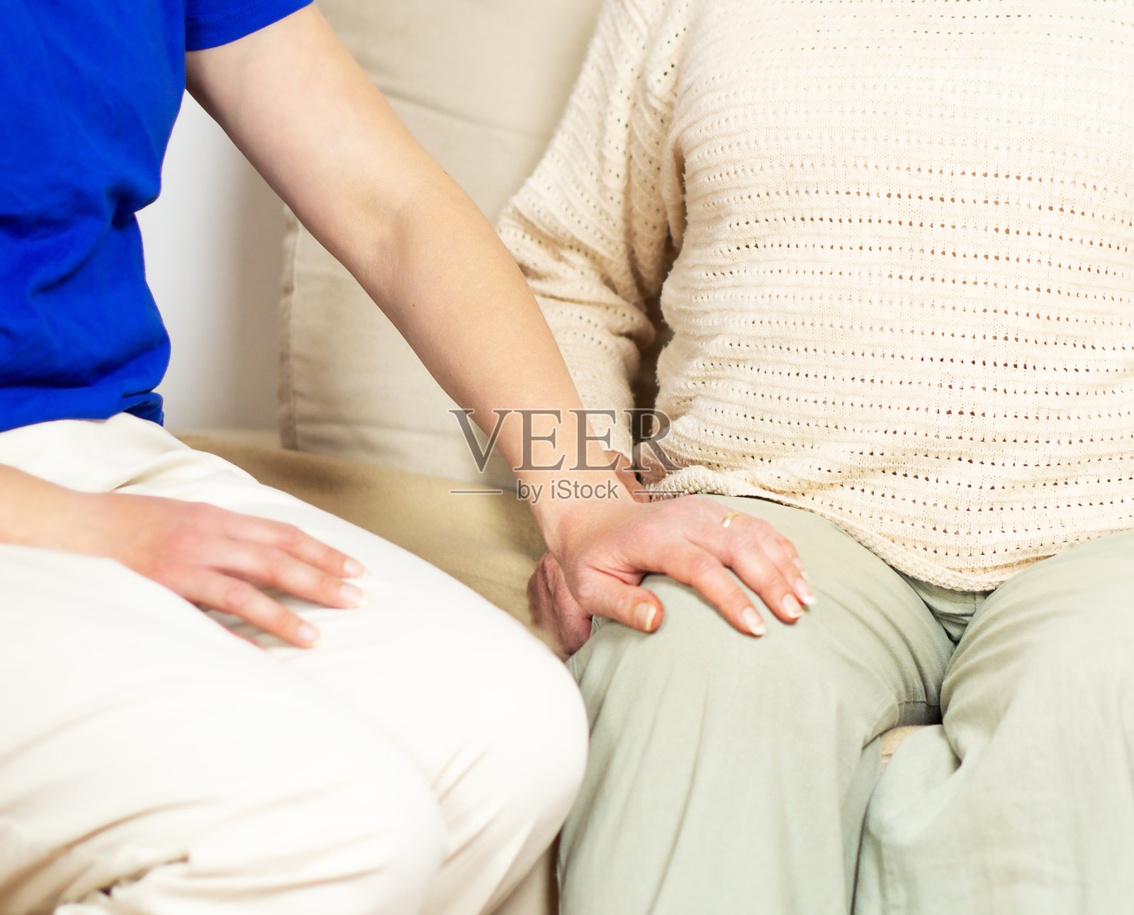 年轻护工帮助膝盖疼痛的老年妇女。照片摄影图片