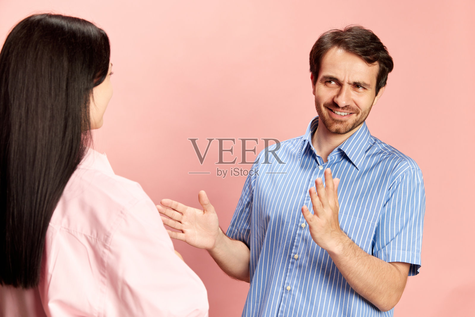 感性的男人和女人交谈，讨论新闻和谣言在粉红色的工作室背景。活泼的谈话和分歧照片摄影图片