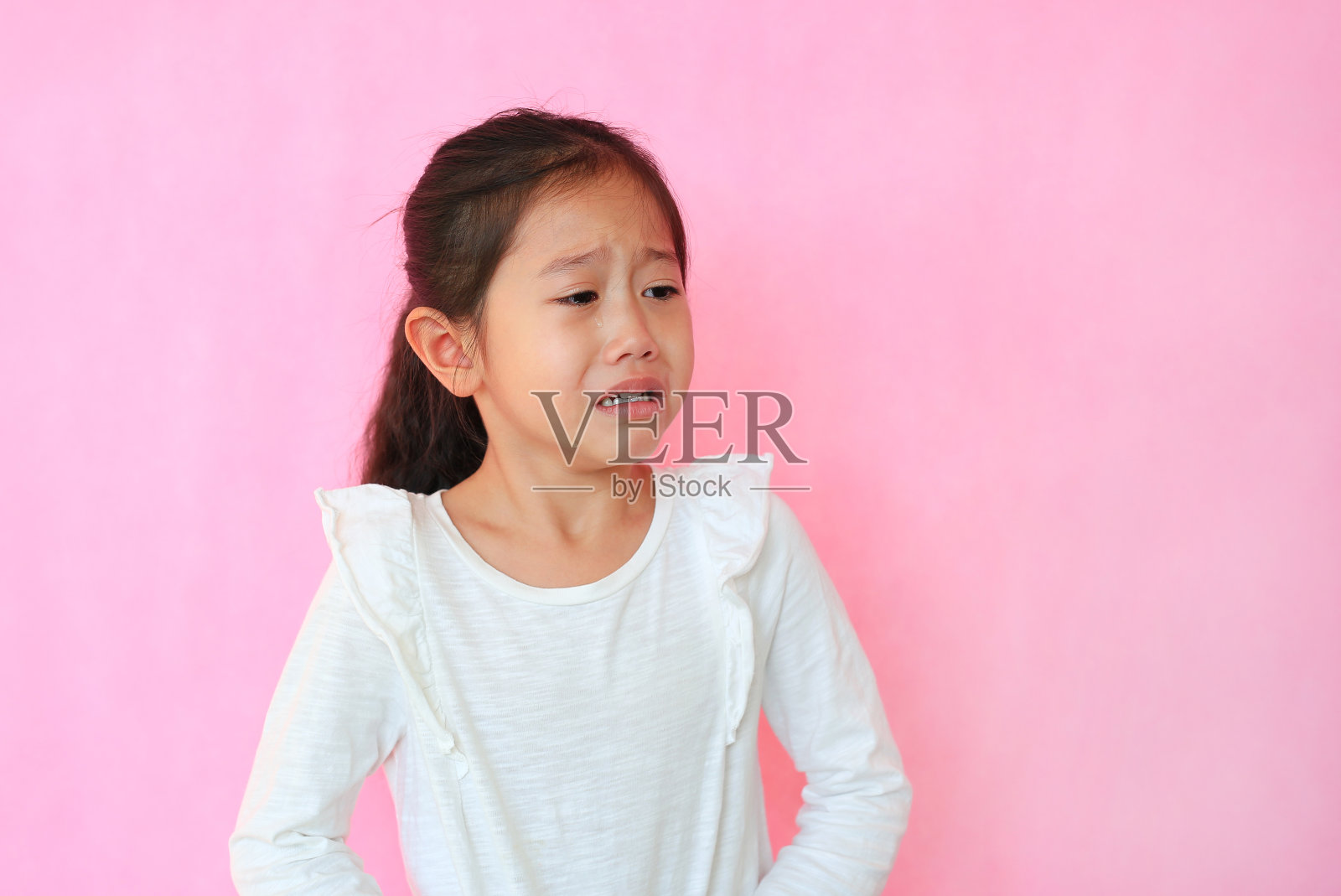 肖像特写亚洲小女孩哭泣孤立的粉红色背景与复制空间。带着悲伤表情的孩子。照片摄影图片