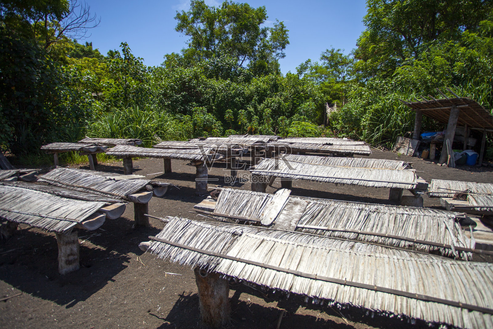 在东巴厘岛Klungkung果阿拉瓦的果阿拉瓦海滩或Pantai果阿拉瓦的天然制盐商或盐农，用隐蔽的木制蒸发盘将海水放在阳光下，水蒸发后留下纯净的海盐。照片摄影图片