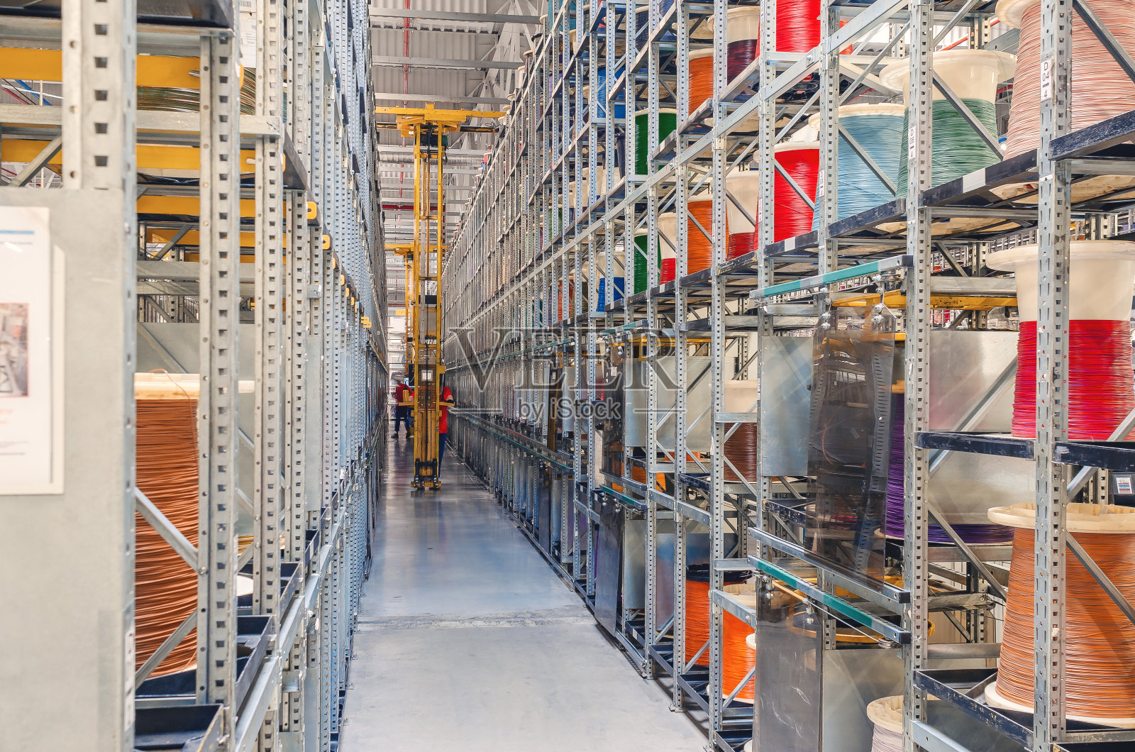 现代化仓库内部：金属架上彩色线缆盘绕，工厂内有叉车照片摄影图片