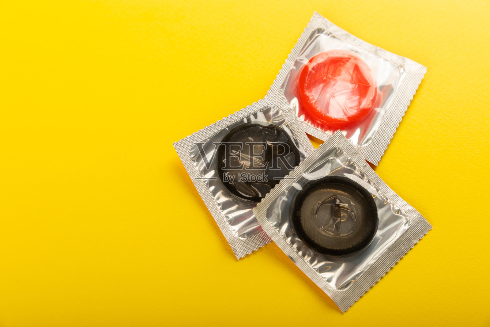 黄色背景上的彩色避孕套。使用避孕套以减少怀孕或性传播疾病的机会。安全性行为的概念。副本的空间。平躺照片摄影图片