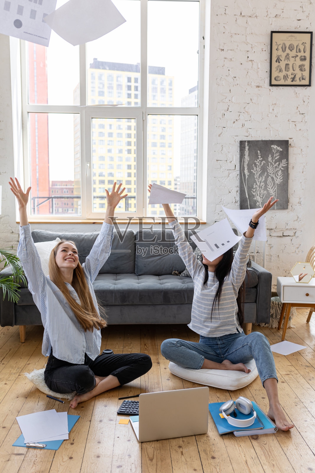 两个年轻的女性坐在家里的地板上一起做这个项目。庆祝成功。创意工作概念，创意、自由职业和创业。千禧年的女孩照片摄影图片