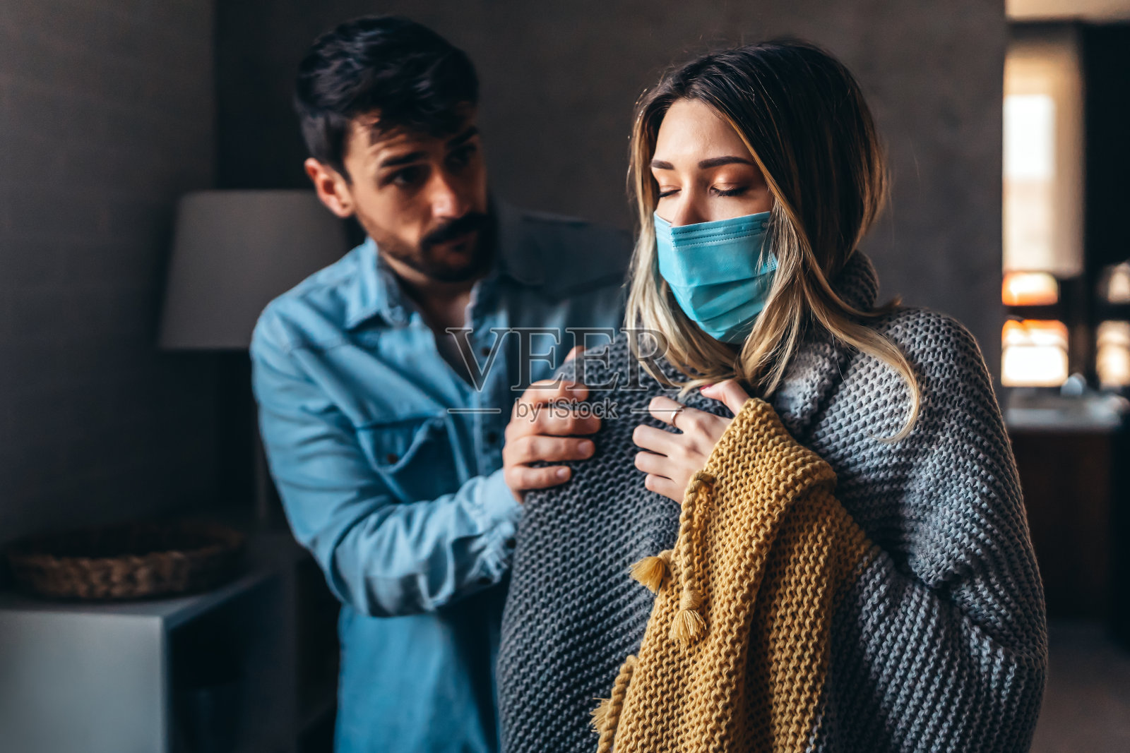 冻僵的夫妇盖着毯子。一个男人和一个女人在寒冷的房间里裹着温暖的毯子。照片摄影图片