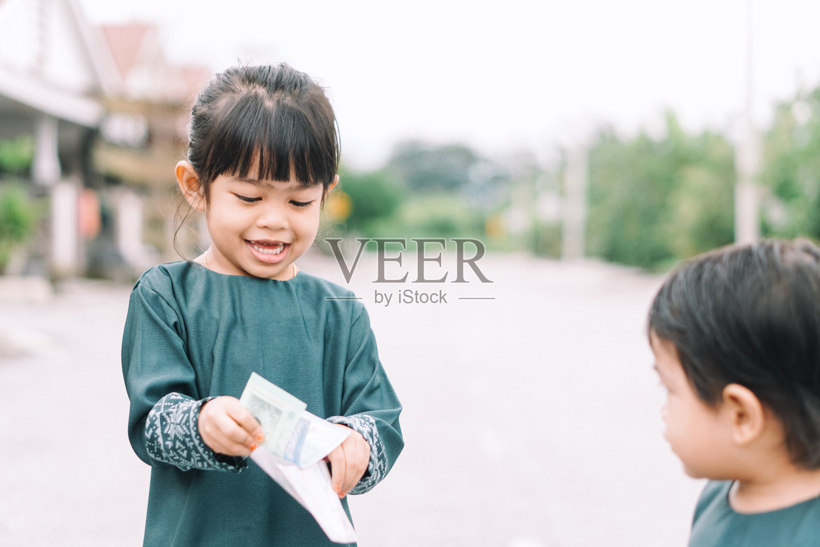 可爱的马来女孩在开斋节或开斋节庆祝活动中，马来传统服装显示他收到钱后的快乐反应照片摄影图片