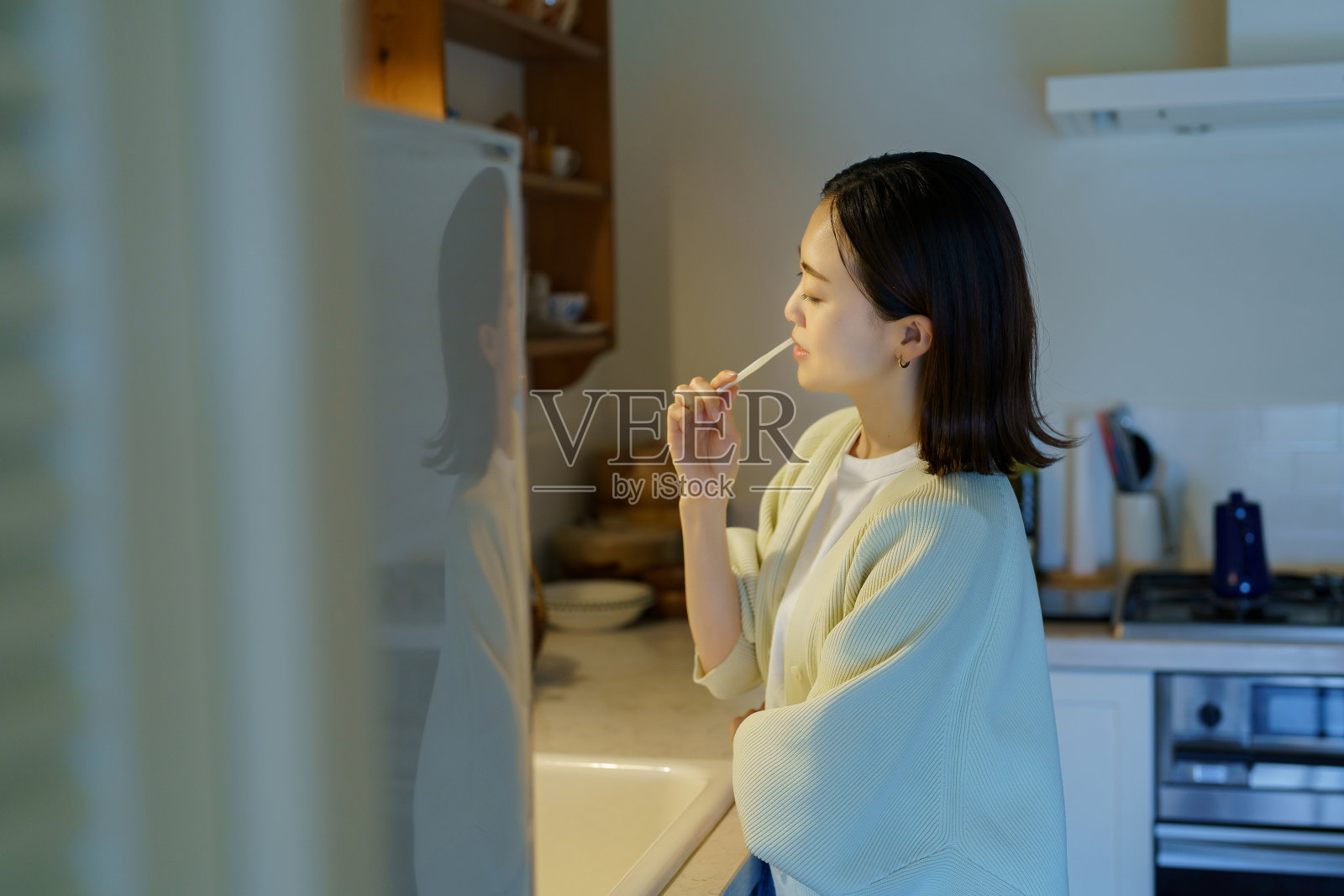 在黑暗的厨房里刷牙的女人照片摄影图片