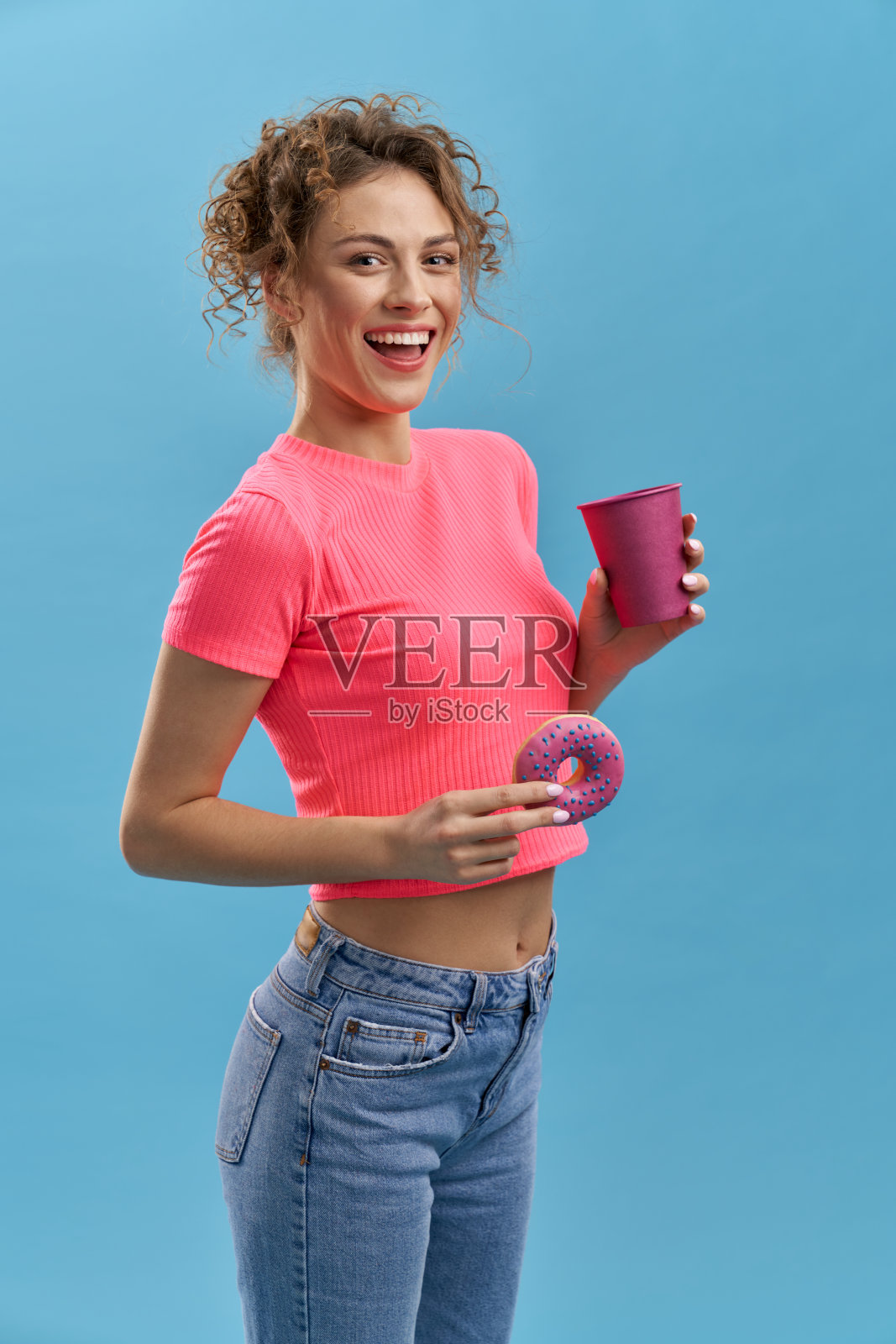 美丽的年轻女性拿着甜甜圈和杯子。照片摄影图片