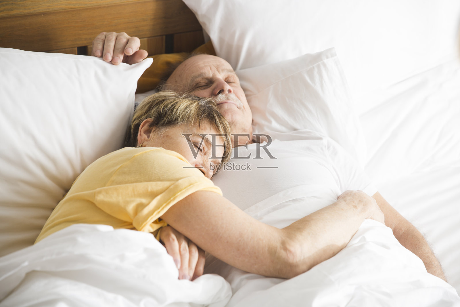 健康的老年人的生活方式。一对慈爱的老夫妇在家里的床上拥抱着睡觉照片摄影图片