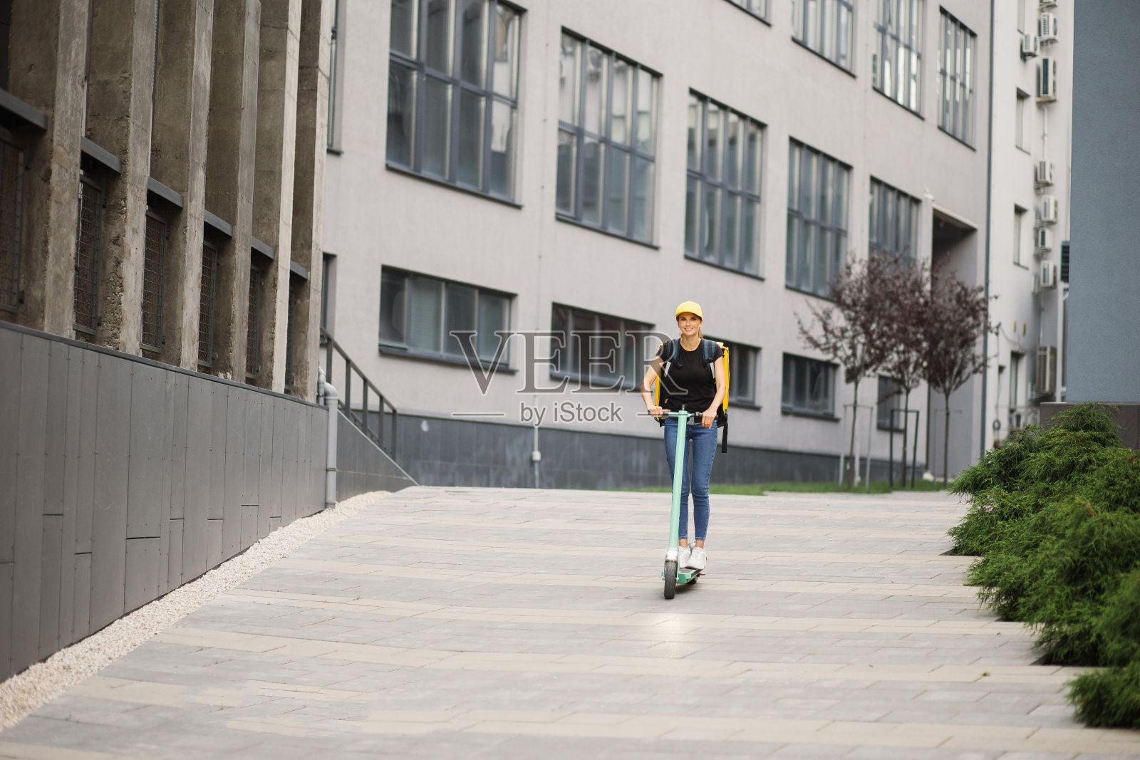带着等温背包的女快递员骑着她的电动摩托车照片摄影图片