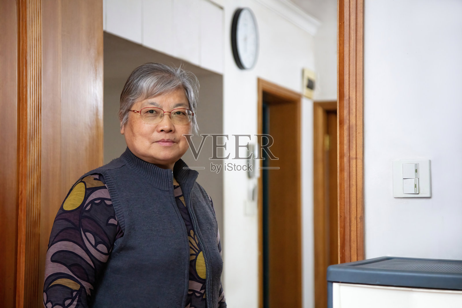这位东亚老太太站在客厅里，面带微笑地看着镜头照片摄影图片