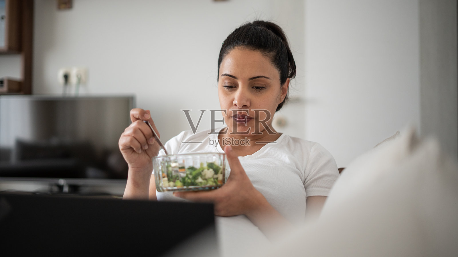 年轻漂亮的孕妇一边吃沙拉一边用笔记本电脑照片摄影图片