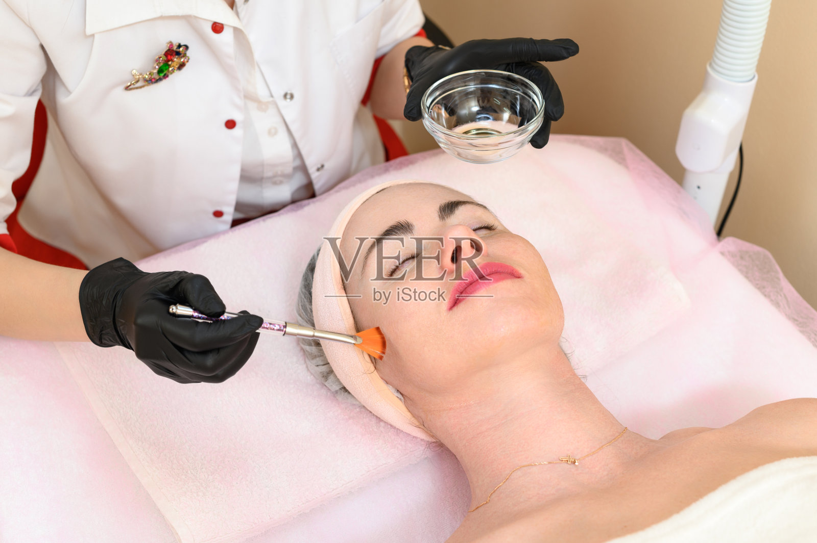 美容师用宽刷把液体凝胶涂在脸上照片摄影图片