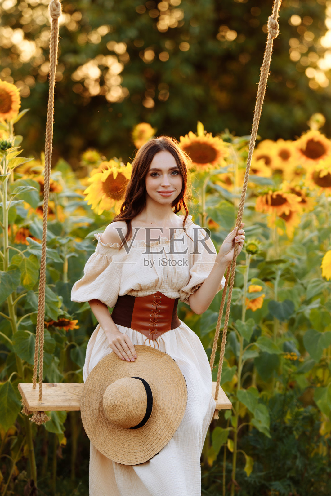 穿着裙子的女人在向日葵地里荡秋千照片摄影图片