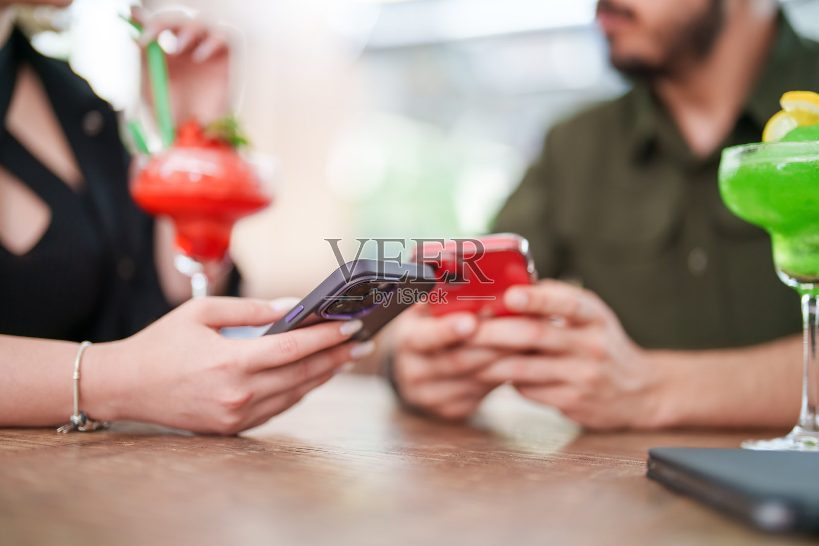 朋友们在酒吧喝着鸡尾酒玩手机。照片摄影图片