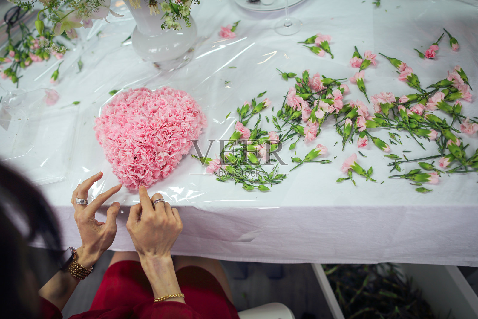 亚洲女人参加插花课程，用大量康乃馨制作心形花束，在母亲节送给妈妈照片摄影图片